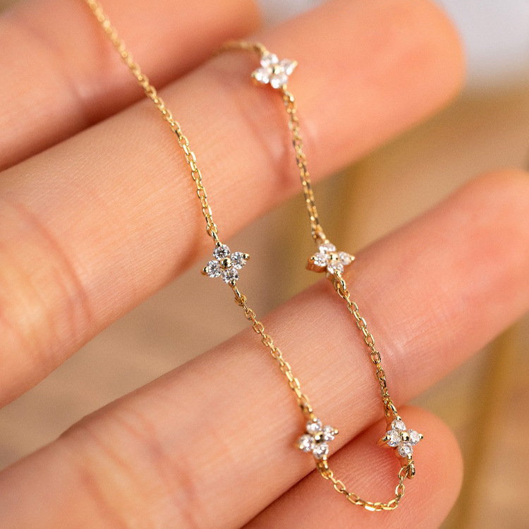 Close-up of gold S925 silver four leaf clover CZ station bracelet charms